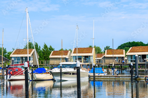 Boats mooring in Lauterbach port with houses on water on sunny summer day, Ruegen island, Baltic Sea, Germany
