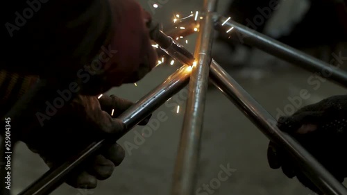 Workers in the mask are welding steel in workshop	