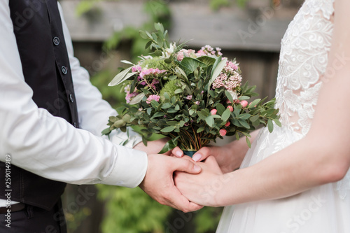 Bridal bouquet of pink and white flowers, roses and peonies, in the hands of a girl, wedding dress, the groom in a suit.