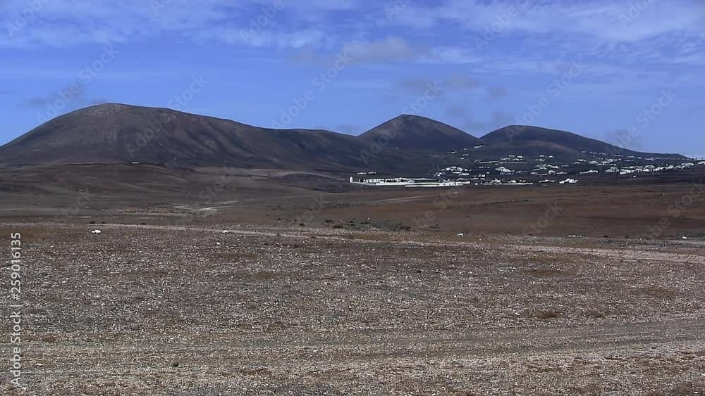 Panorama of Lanzarote with vulcanos, hills, mountains and basalt or lava field in front, Spain.