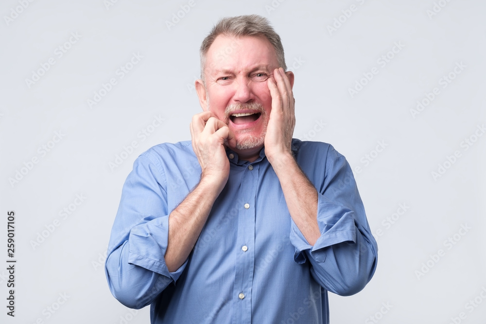 crazy senior man in blue shirt crying receiving bad news. crazy senior man in blue shirt crying receiving bad news.