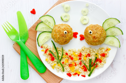 Fototapeta Klopsiki rybne z owsianką i warzywami na zabawny i zdrowy obiad dla dzieci, kompozycja sztuki jedzenia