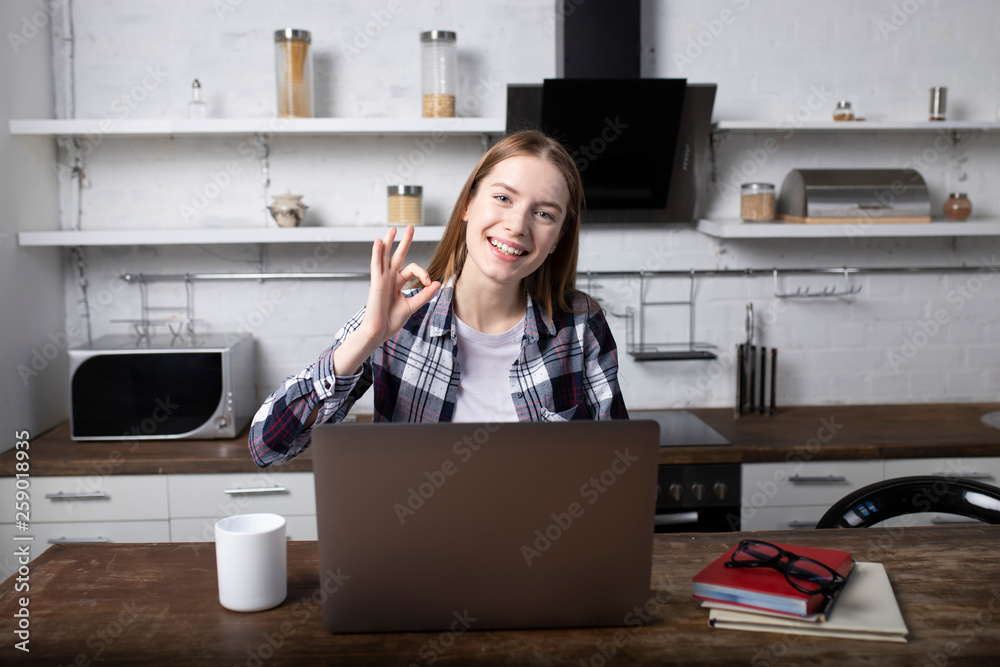 Happy woman working at home in the morning. Girl drinking coffee. She is using her laptop Happy woman working at home in the morning. Girl drinking coffee. She is using her laptop
