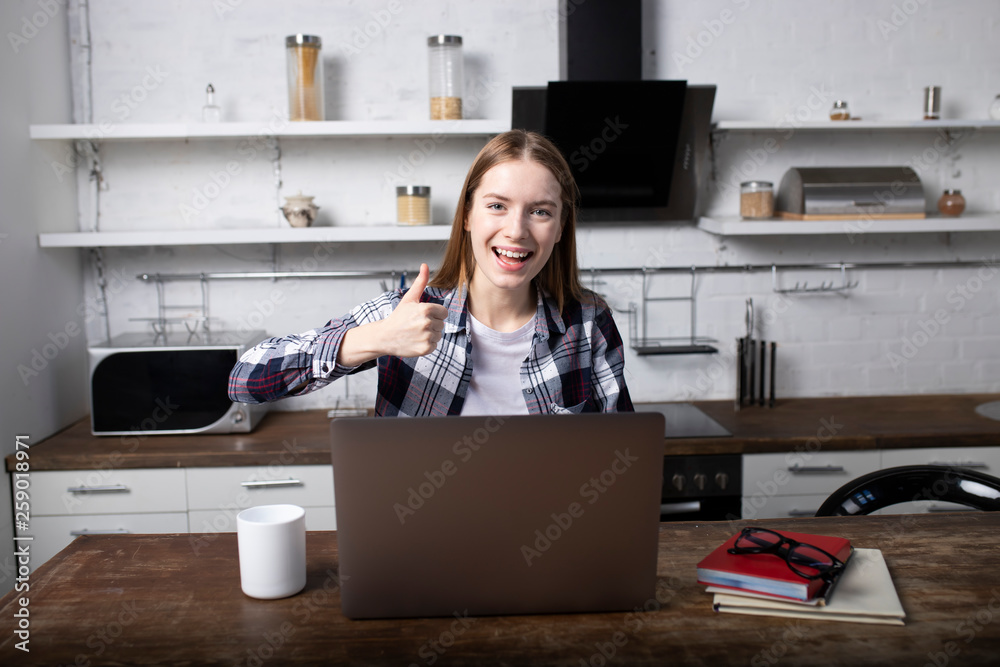 Happy woman working at home in the morning. Girl drinking coffee. She is using her laptop Happy woman working at home in the morning. Girl drinking coffee. She is using her laptop