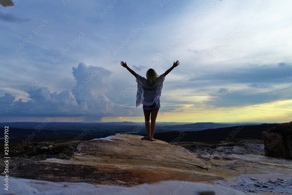 Woman in the top of mountain, sunset light, beauty summer landscape. Standing on top of cliff. Capitólio, Minas Gerais, Brazil