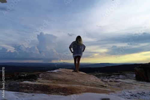 Woman in the top of mountain, sunset light, beauty summer landscape. Standing on top of cliff. Capitólio, Minas Gerais, Brazil