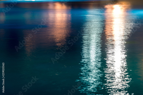 Abstract background, texture of blue water with multicolored highlights on it