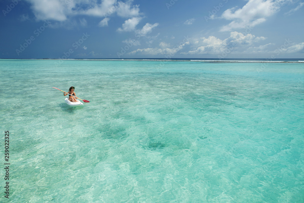 Pretty woman swimming in canoe and relax in the sea. Happy island lifestyle. White sand, crystal-blue sea of tropical beach.  Ocean beach relax, kayaking, travel to Maldives islands