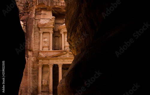 Petra treasure ancient architecture building inside canyon dark rock walls frame famous world heritage touristic site