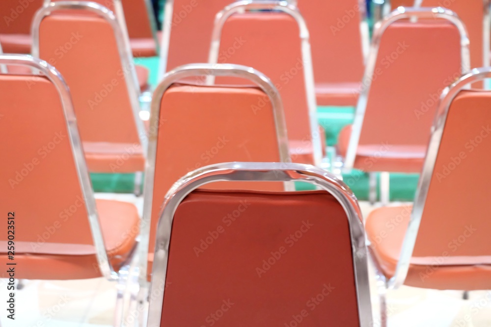 A row of orange modern chairs in exhibition hall with blurred green floor A row of orange modern chairs in exhibition hall with blurred green floor