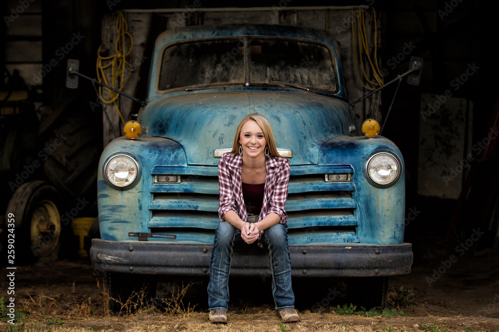 Φωτογραφία Attractive young woman sitting on the bumper of an old truck