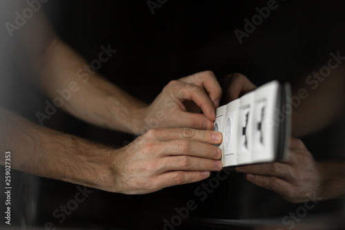 Close-up of an electrician's hand without any tools and gloves disassembling a white electrical outlet on a black glass wall