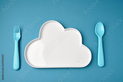 Blue plastic dishes and white plate on blue background. Concept