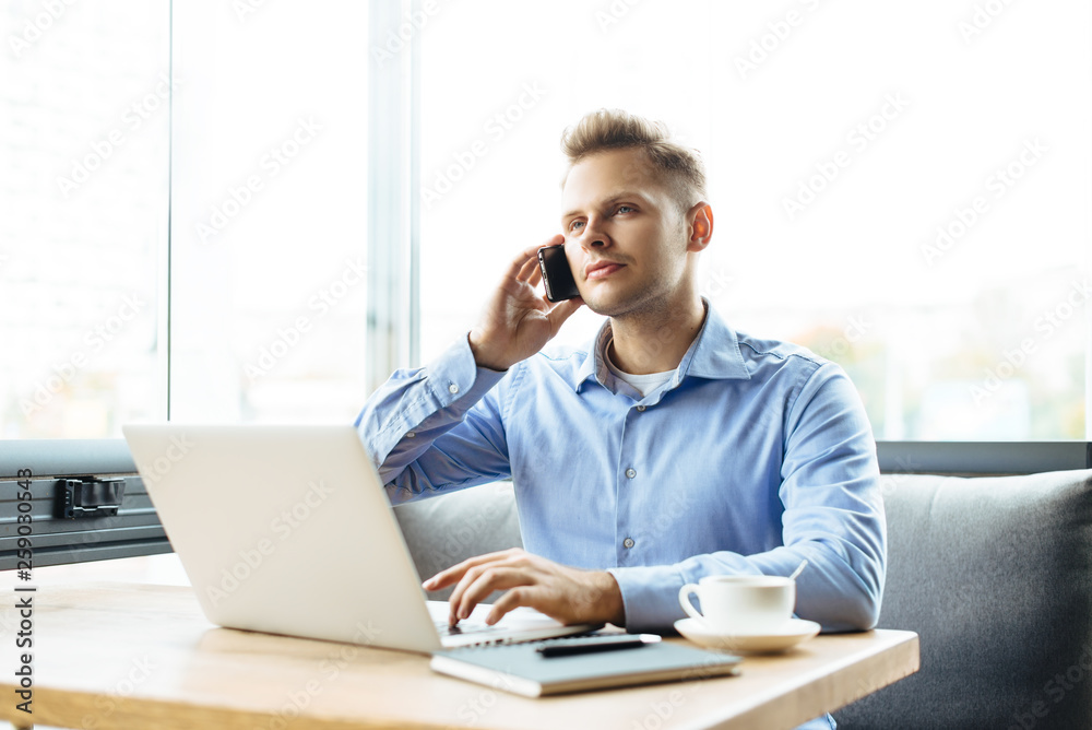 Stylish young man calling by the phone to solve business problems. Online consultation by phone. Freelancer discussing the development and planning of his online project. Outsourcing. Mobile services. Stylish young man calling by the phone to solve business problems. Online consultation by phone. Freelancer discussing the development and planning of his online project. Outsourcing. Mobile services.