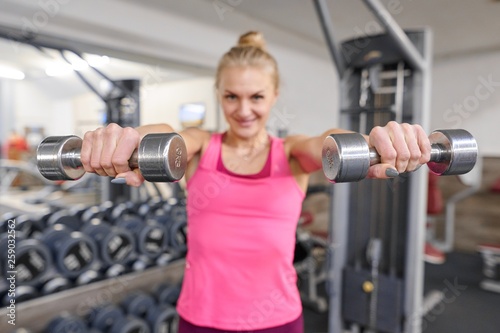 Young sporty blond woman in the gym. Woman holding metal weights, focus on kettlebells. People fitness sport healthy lifestyle concept