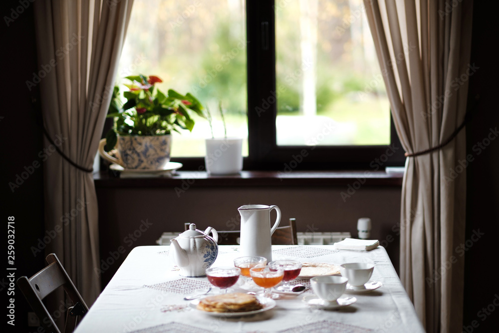 Fototapeta premium Rustic interior of a country house. Dining table in the dining room opposite the window.