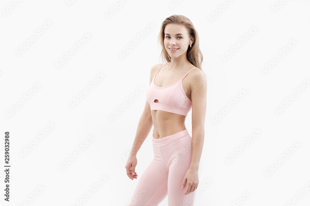Fototapeta premium Sports blonde girl in red training clothes in the studio on a white background.