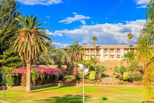 Park and garden with yellow palace building hidden behind tall palms, Windhoek, Namibia