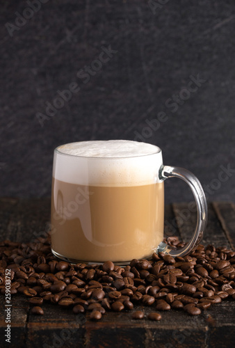 Fototapeta Naklejka Na Ścianę i Meble -  Cafe Latte Coffee in a Clear Glass Mug in a Dark Environment