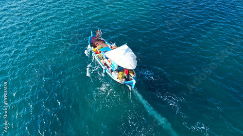Aerial drone top view photo of red wooden traditional fishing boat in turquoise sea shore of Mykonos island, Cyclades, Greece