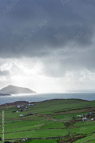 a view of the wild atlantic way off the coast of the ring of kerry in ireland showing skellig michael and surrounding islands in beautiful strong light with cloudy skies 