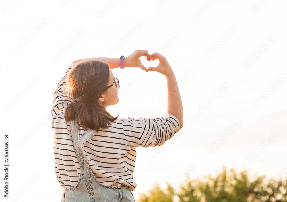 pretty girl making hands in heart shape in sunset pretty girl making hands in heart shape in sunset