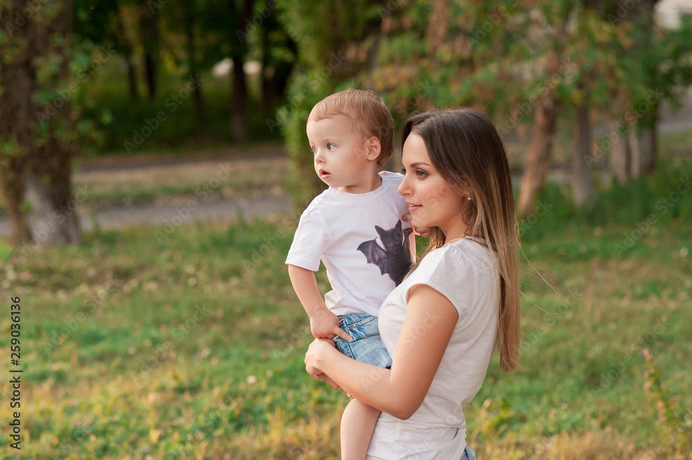 happy mother holds cute smiling son in the park happy mother holds cute smiling son in the park