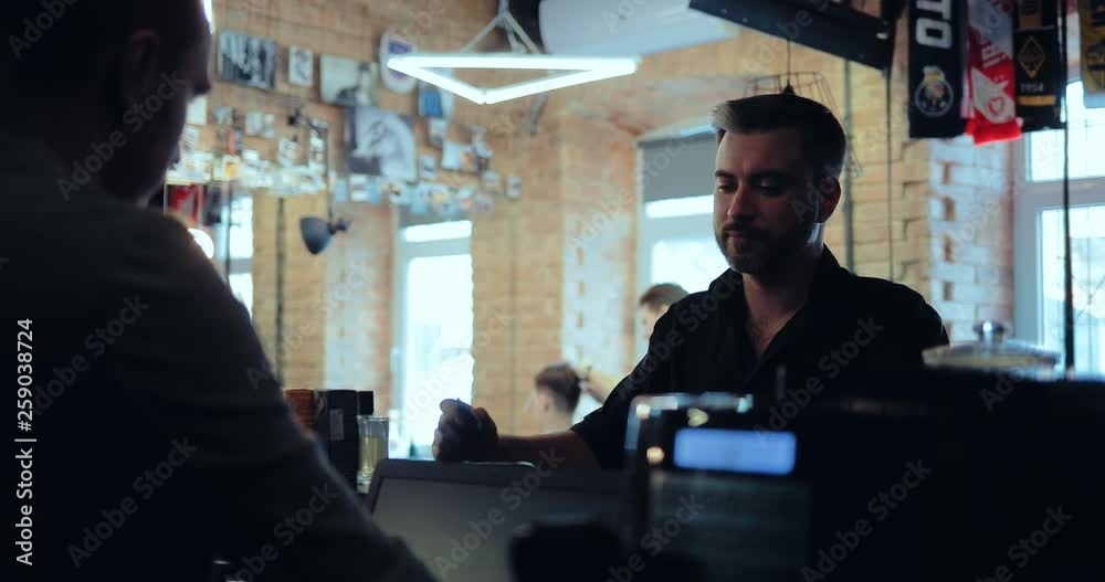 Smiling man stands at the reception desk and talks. Hair Salon