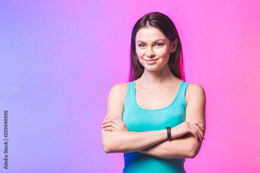 Smiling sports woman standing with arms folded and looking at ca Smiling sports woman standing with arms folded and looking at ca