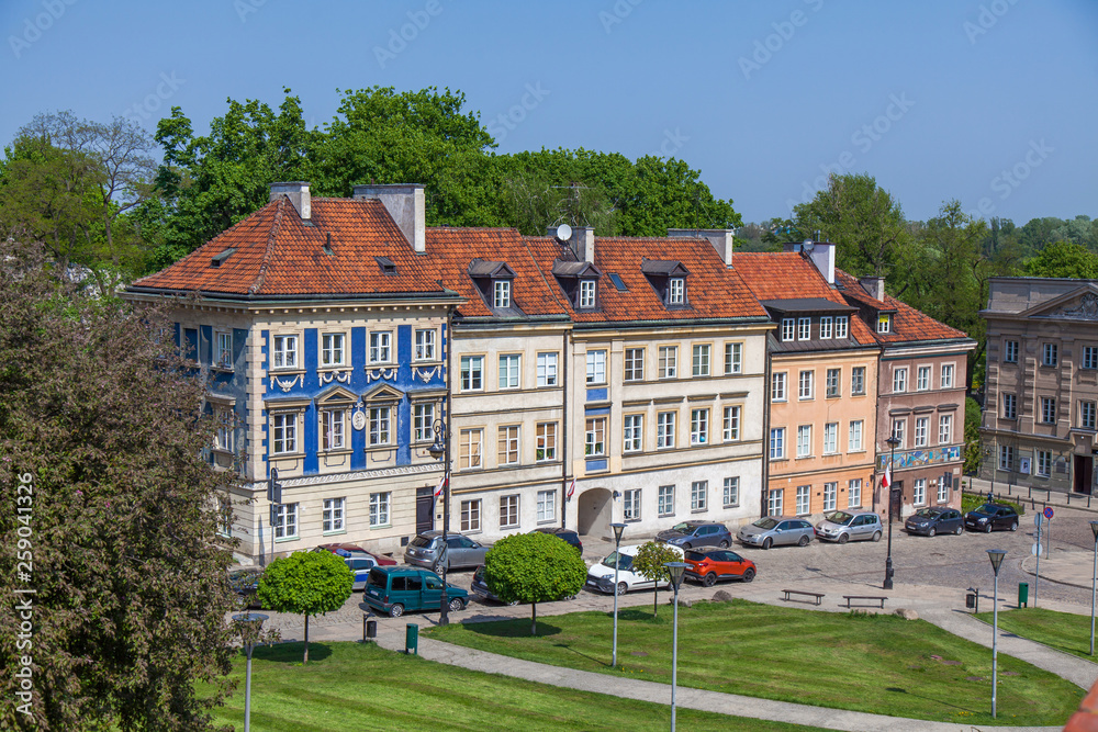 Early color houses surrounded by green trees. Warsaw