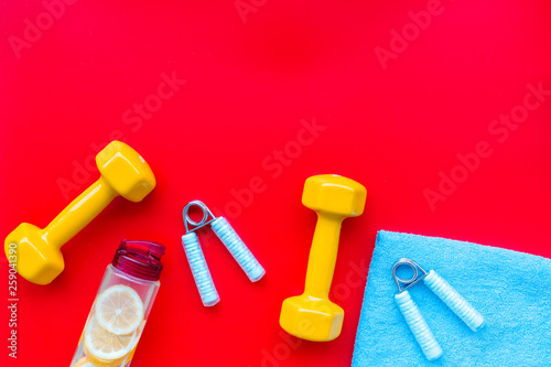 Fitness set with bars, towel, bottle of water and wrist builder on red background top view mock up © 9dreamstudio