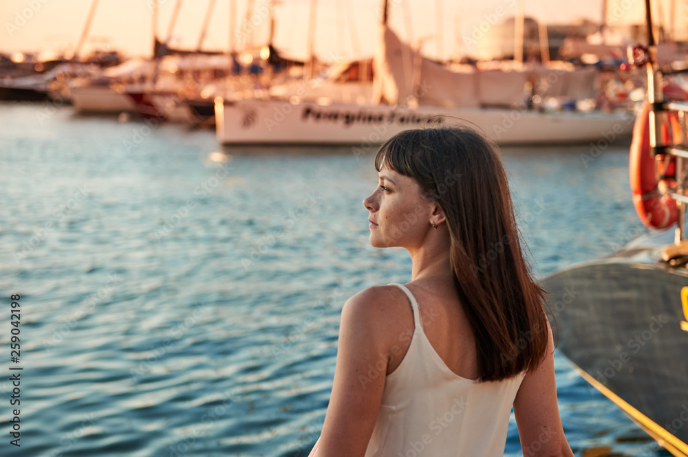 Portrait of a beautiful woman with freckles on the background of the sea and beautiful yachts