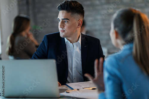 Young businessman ignoring his female colleague while she talking to him in the office. photo