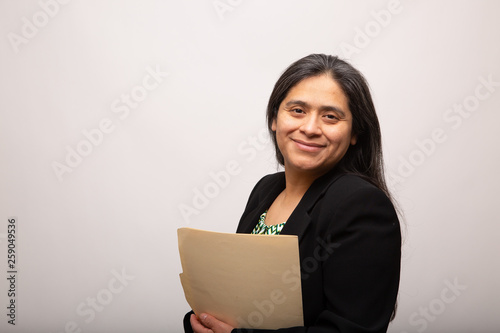 Hispanic Businesswoman Holding Folder Smiles At Camera