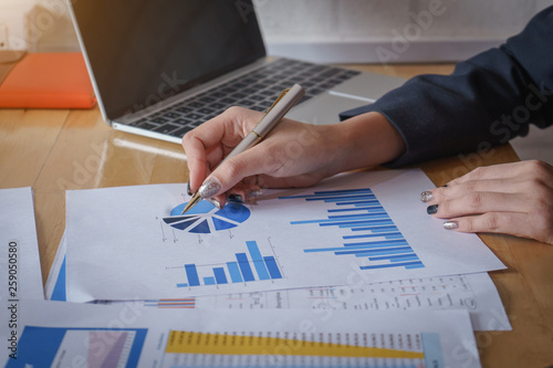 Businesswomen analyzing data financial reports on wooden table.