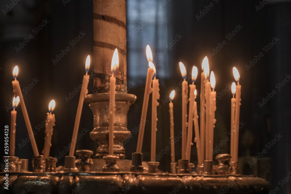 wax candles in a candlestick burn slowly in the darkness of the temple