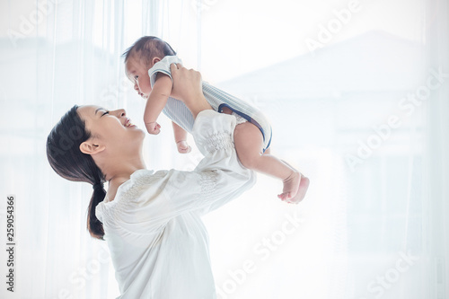 Mother lifting and playing with newborn baby, baby talking to mother. Health care family love together mother’s day concept