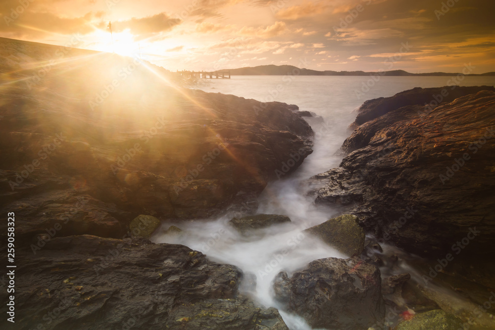 Fototapeta premium Beautiful natural seascape wave moving on the rock during sunrise