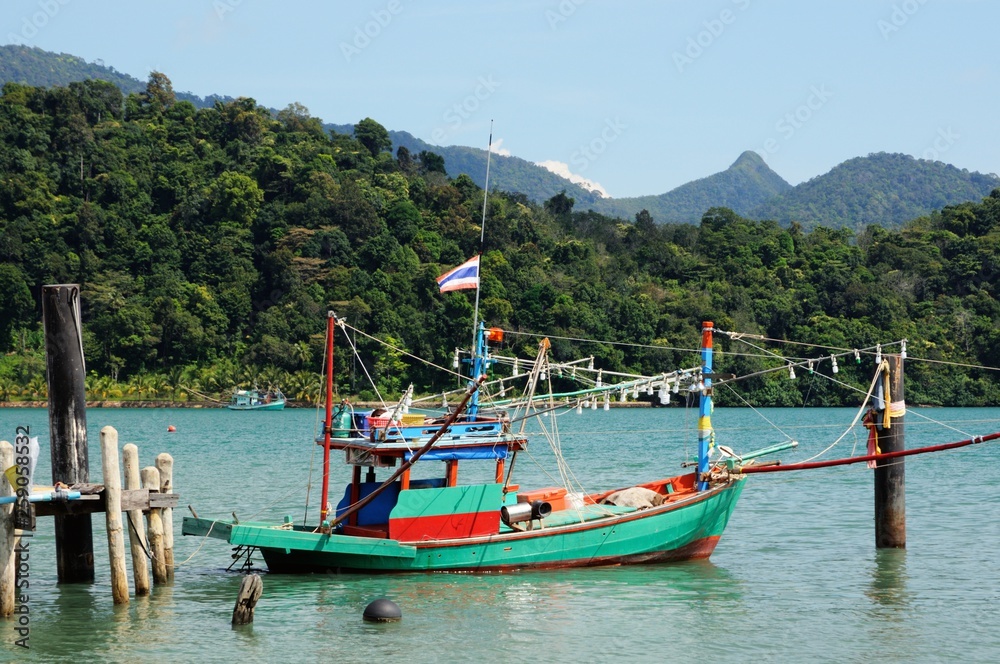 Thai fishing boat at wooden pier on the Koh Chang island, Thailand.