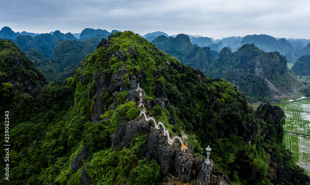 Aerial drone photo - A woman poses with the dragon atop the Hang Mua hike.  Mountains of northern Vietnam.
