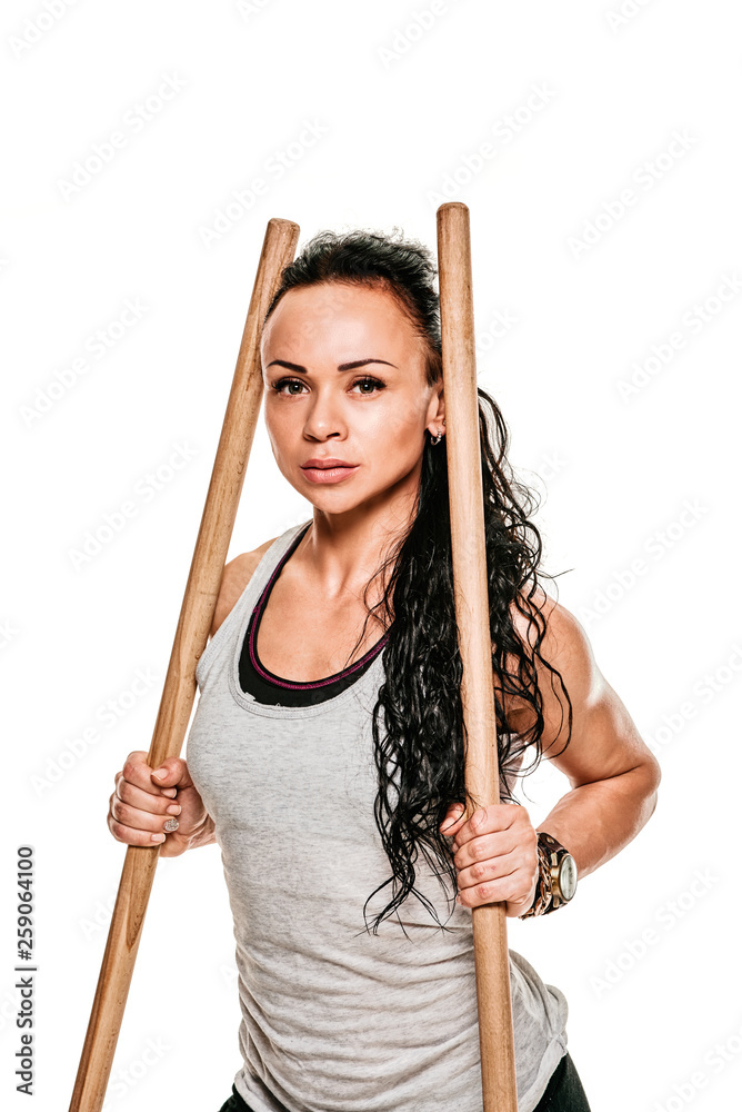 Young female bodybuilder training with gymnastic wooden sticks
