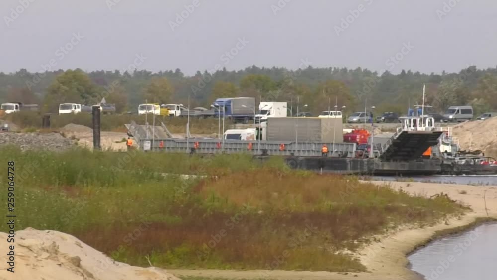 A line of trucks lined up on the shore. River freight ferry transports cars and people. A line of trucks lined up on the shore. River freight ferry transports cars and people.