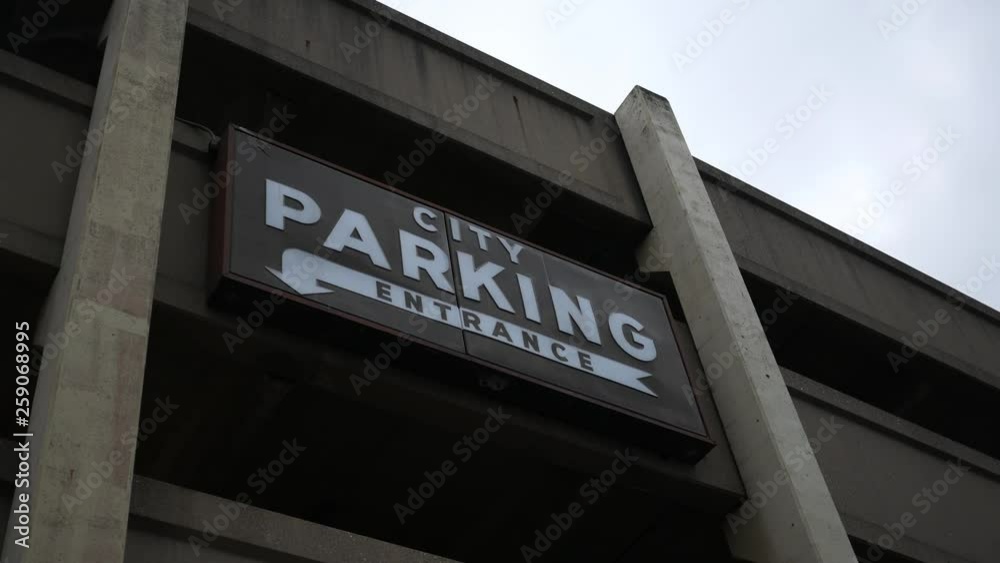 A city parking entrance sign for a parking garage on overcast evening A city parking entrance sign for a parking garage on overcast evening