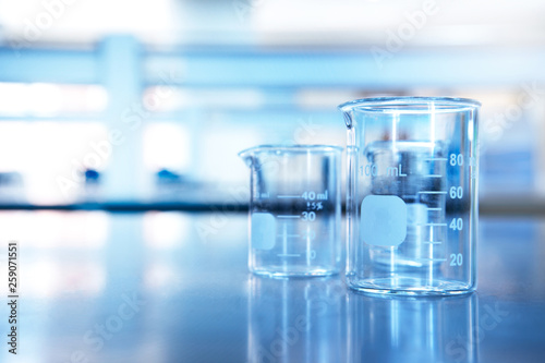 two glass beaker on chemistry science laboratory table blue research and education background