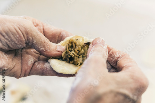 Woman making tasty dumplings in kitchen.