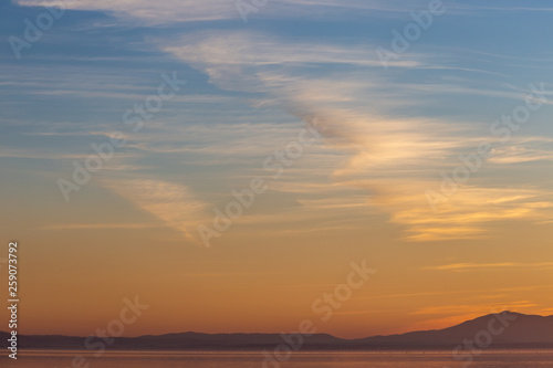 Beautiful view of Trasimeno lake (Umbria, Italy) at sunset, with orange and blue tones in the sky © Massimo