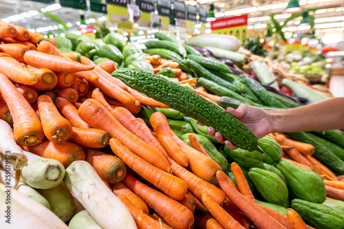 Woman hand with zucchini. Vegetable background, fresh and shiny organic zucchinis or courgettes on a local food market, Bali island.