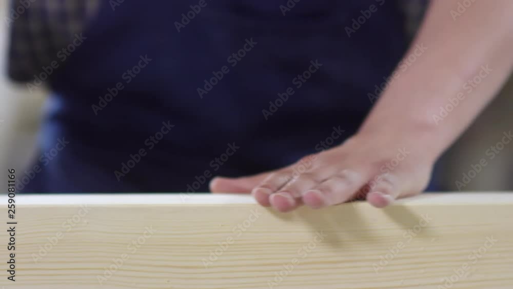 Close up of male hand checking smoothness of wooden plank and then sanding it with orbital sander Close up of male hand checking smoothness of wooden plank and then sanding it with orbital sander
