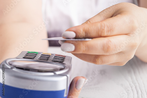 Paying with credit card. Female inserting chip card into payment terminal device
