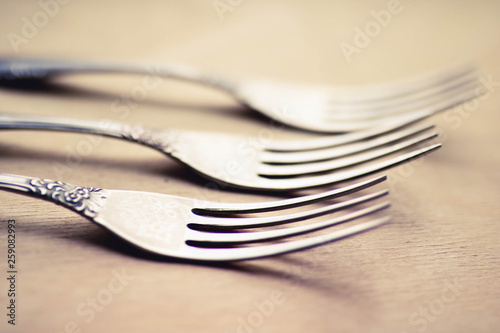 Three antique silver forks close up view. Blurred background.